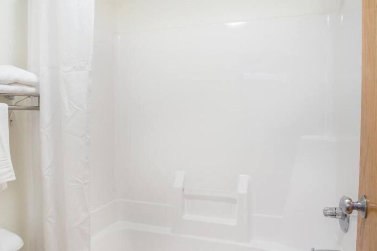 A bathroom with a shower, a towel rack, and a wooden door.