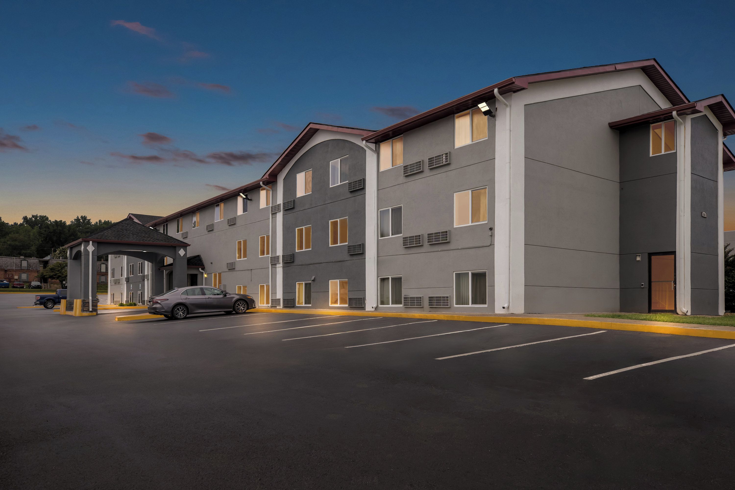 Un hôtel à plusieurs étages, doté d’un design moderne, comprenant une entrée couverte et un parking.