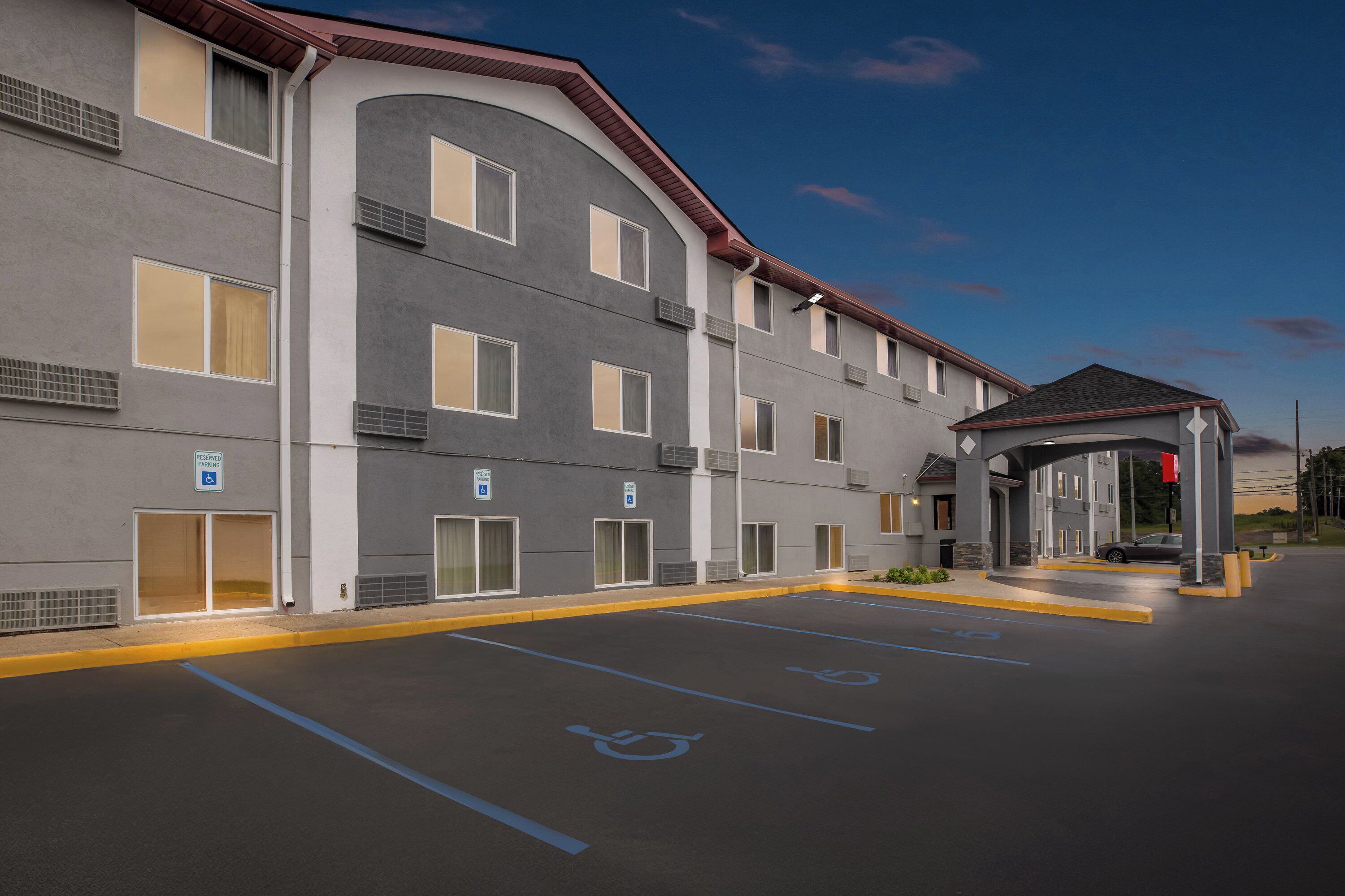 A multi-story hotel with a covered entrance, handicap parking, and a welcoming facade.