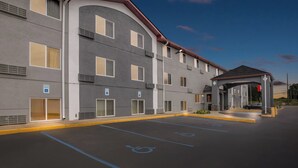 Un hotel de varios pisos con entrada techada, estacionamiento para discapacitados y una fachada acogedora.
