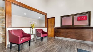 A reception area with two red leather chairs, a small table with a vase, and a sign indicating free Wi-Fi in all rooms.