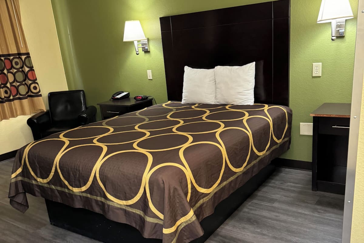 Quarto de hotel com uma cama grande, duas luminárias de cabeceira, uma escrivaninha e uma cadeira.
