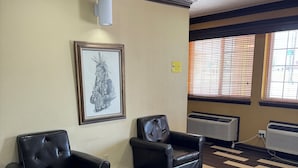 A room with two black leather chairs, a framed artwork on the wall, and a patterned floor. - Super 8 by Wyndham Moriarty (Moriarty)