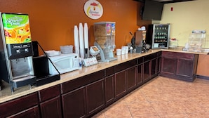 A breakfast area with a coffee machine, juice dispenser, and cereal boxes. - Super 8 by Wyndham Moriarty (Moriarty)