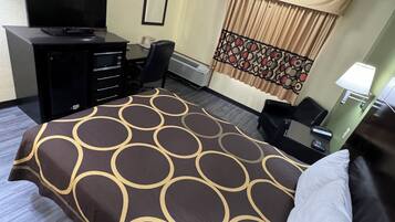A hotel room with a bed, a desk, a chair, a television, and a window with curtains.