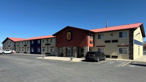 A hotel with a red roof and a Super 8 sign, featuring a parking lot and a black SUV parked in front. - Super 8 by Wyndham Moriarty (Moriarty)