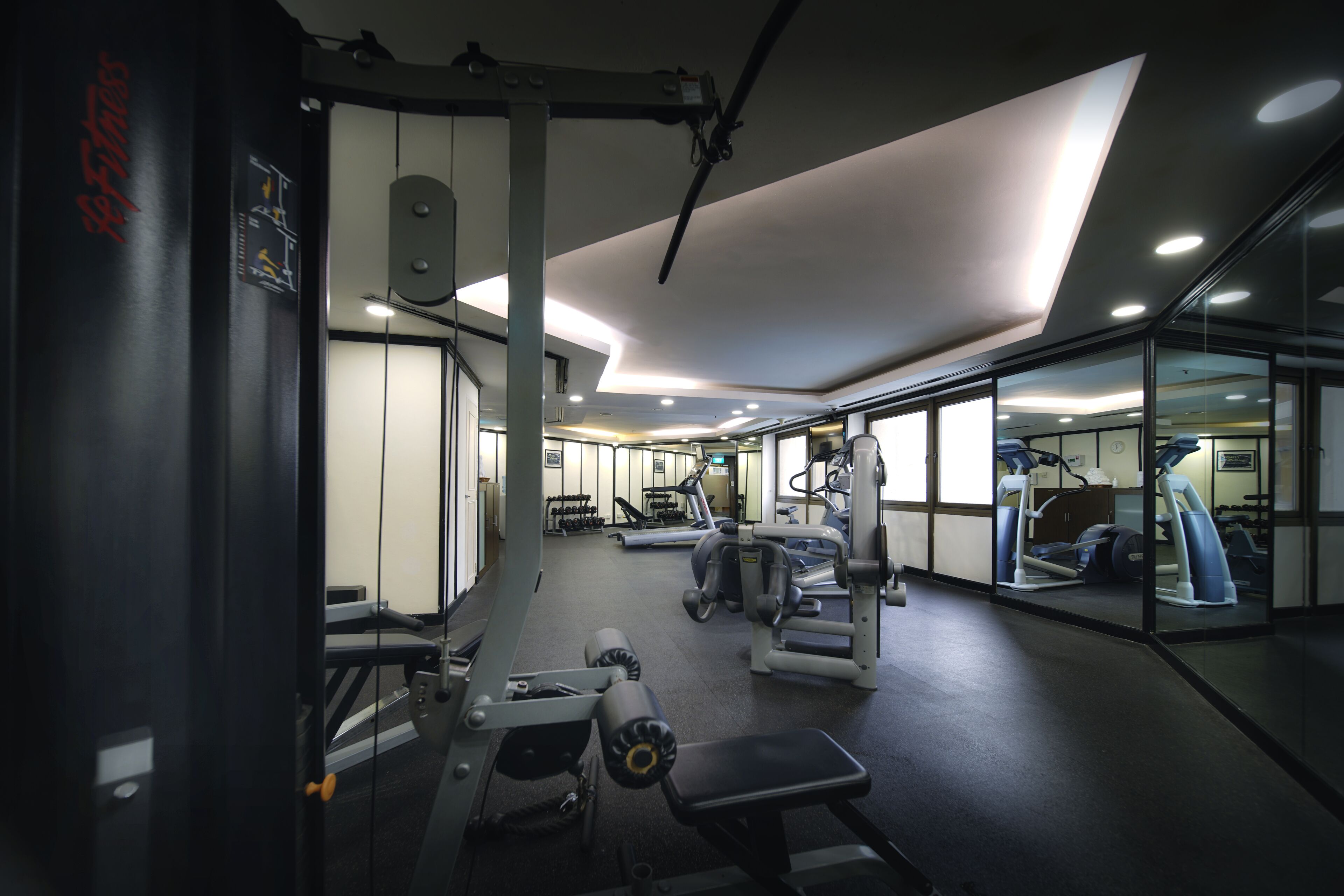 A gym with various exercise equipment, including treadmills and weight machines, and a mirrored wall.