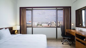 Una habitación de hotel con un ventanal grande, una cama, un escritorio y una silla.