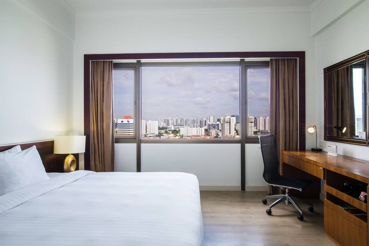 Una habitación de hotel con un ventanal grande, una cama, un escritorio y una silla.