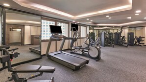 Un gimnasio moderno con cintas de correr, elípticas y equipo de levantamiento de pesas.