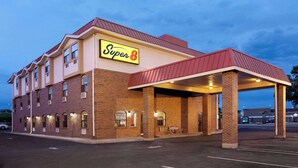 A Super 8 hotel with a brick facade, a covered parking area, and multiple windows.