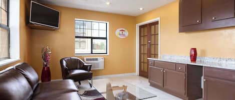A modern kitchen with a glass-top table, brown leather sofa, and a red vase.