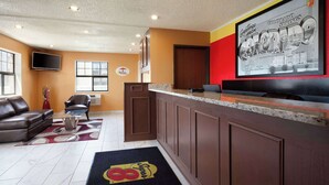 A hotel lobby with a reception desk, a television, a sofa, and a coffee table.