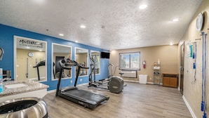 Une salle de sport à domicile équipée d’un tapis de course, d’un vélo elliptique et d’une machine de musculation.