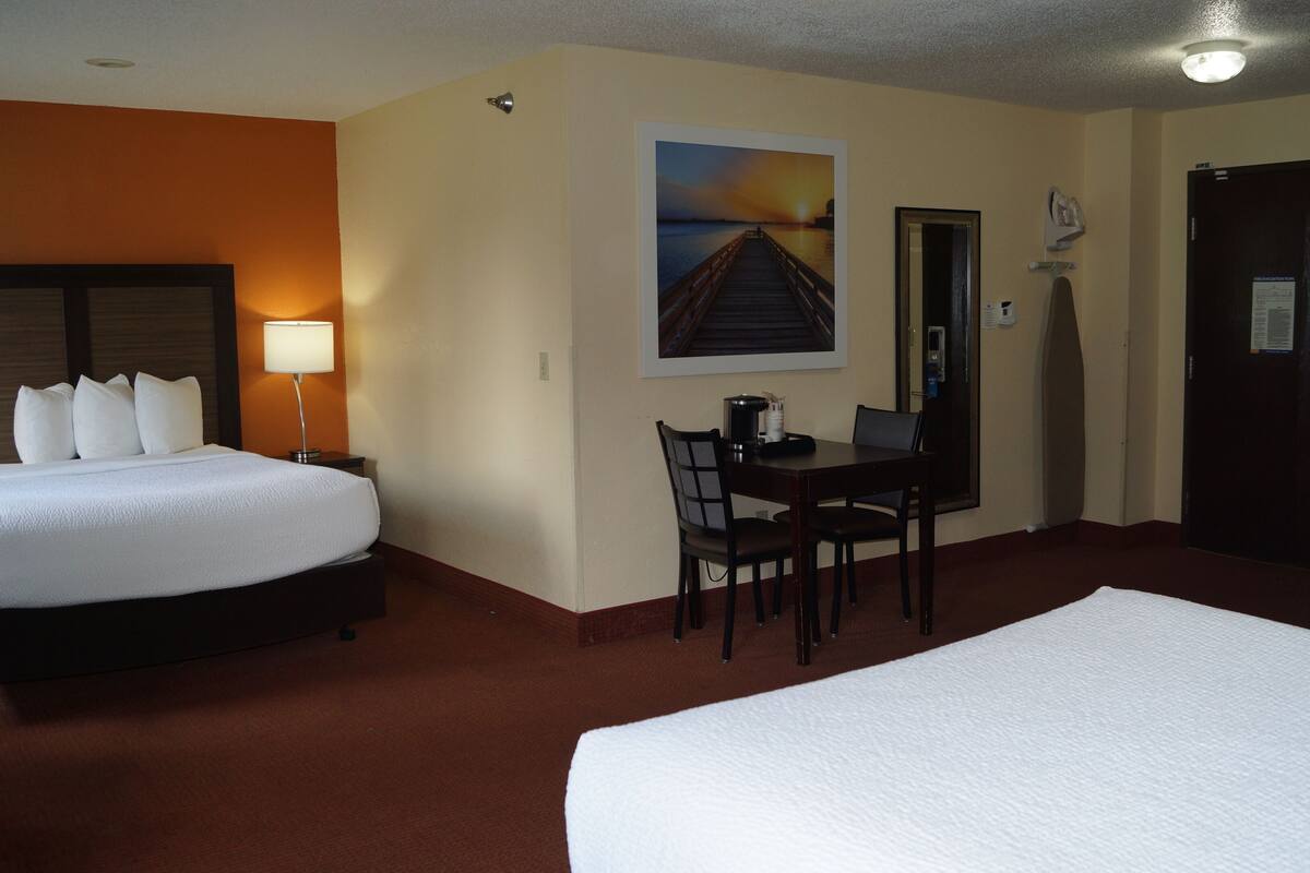 A hotel room with a bed, a desk, a chair, and a painting on the wall.