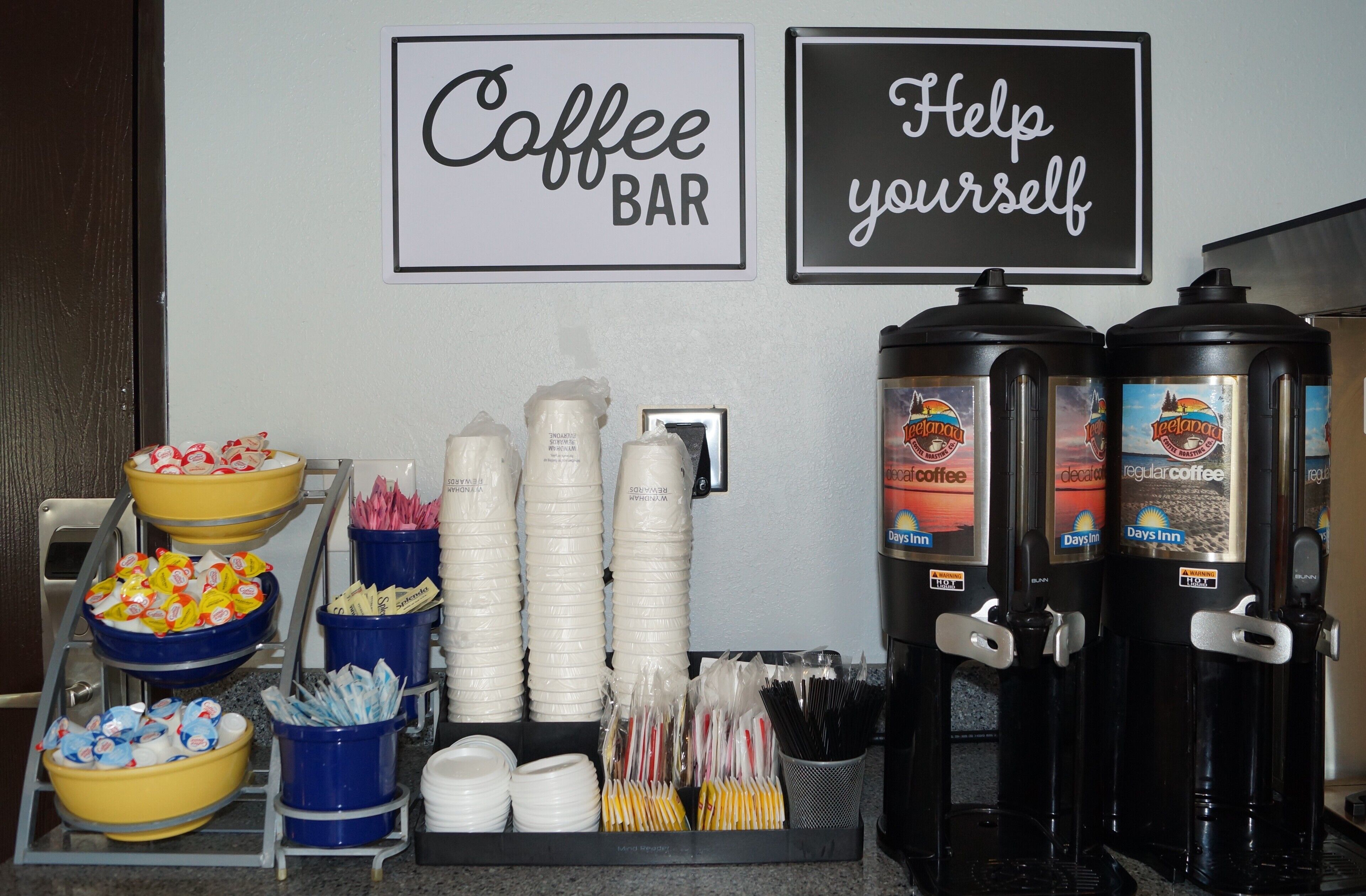 Un bar à café doté de distributeurs à l’effigie de la marque, de bols remplis d’en-cas et de gobelets jetables.