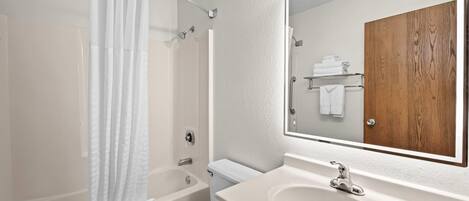 A modern bathroom with a bathtub, toilet, and sink.