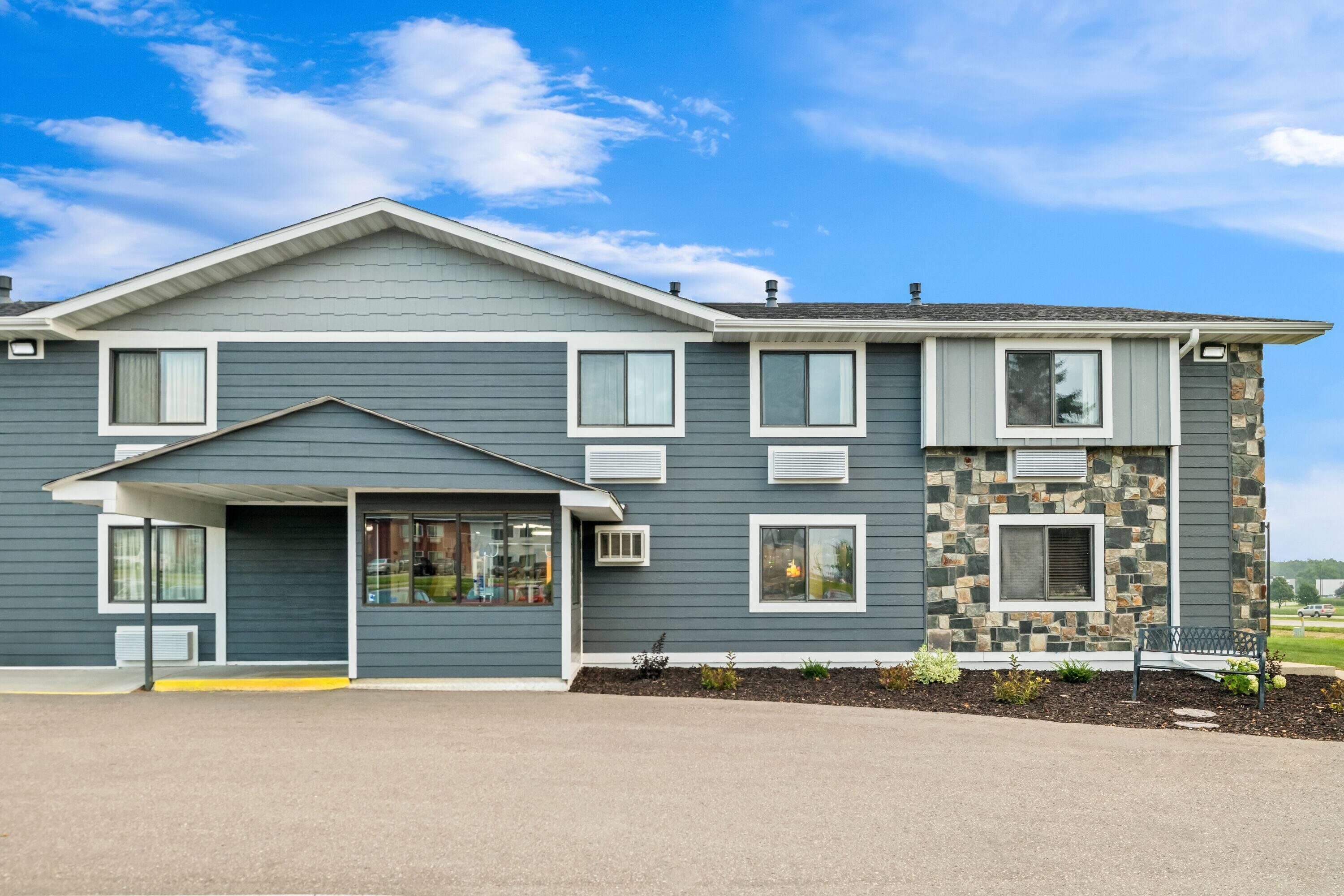 A two-story building with a grey exterior, a stone accent wall, and a covered entrance.