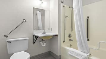 A bathroom with a toilet, sink, shower, and grab bars.