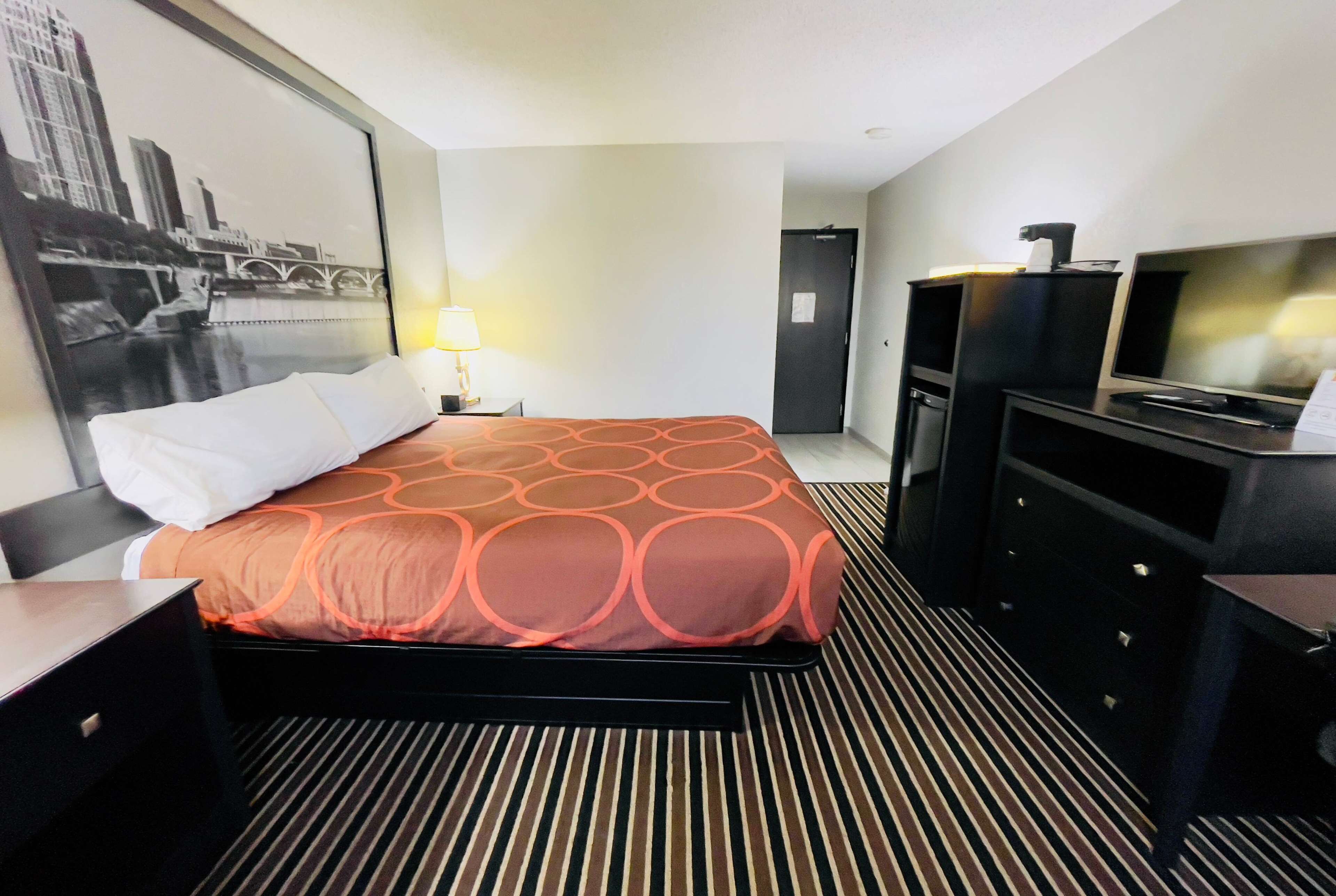 Una habitación de hotel con una cama, un escritorio, un televisor y un televisor instalado en la pared.