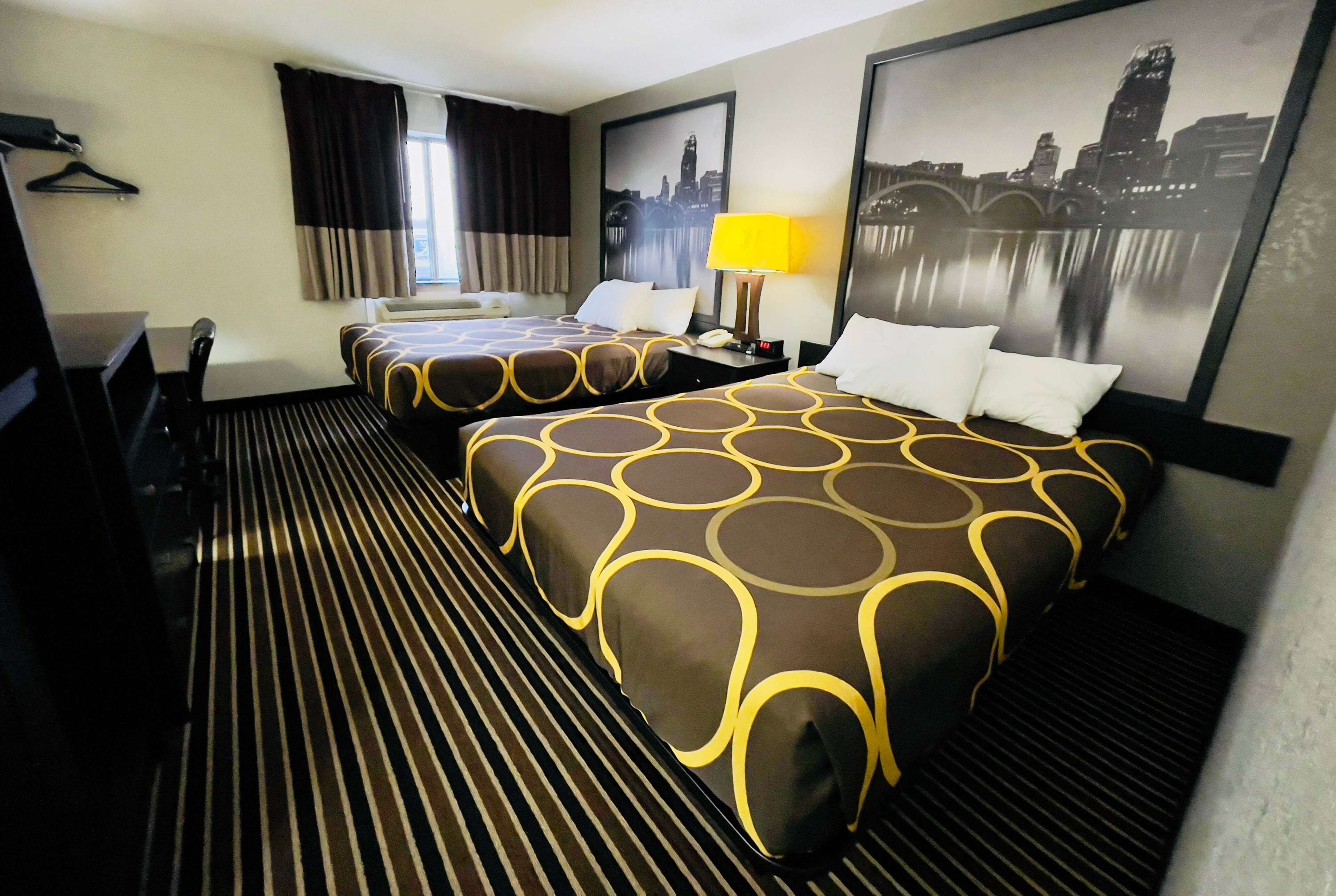 Une chambre d’hôtel avec deux lits, un bureau et une chaise.