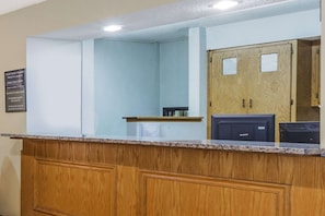 A reception area with a wooden counter, a signboard, and a wooden door with glass panels.