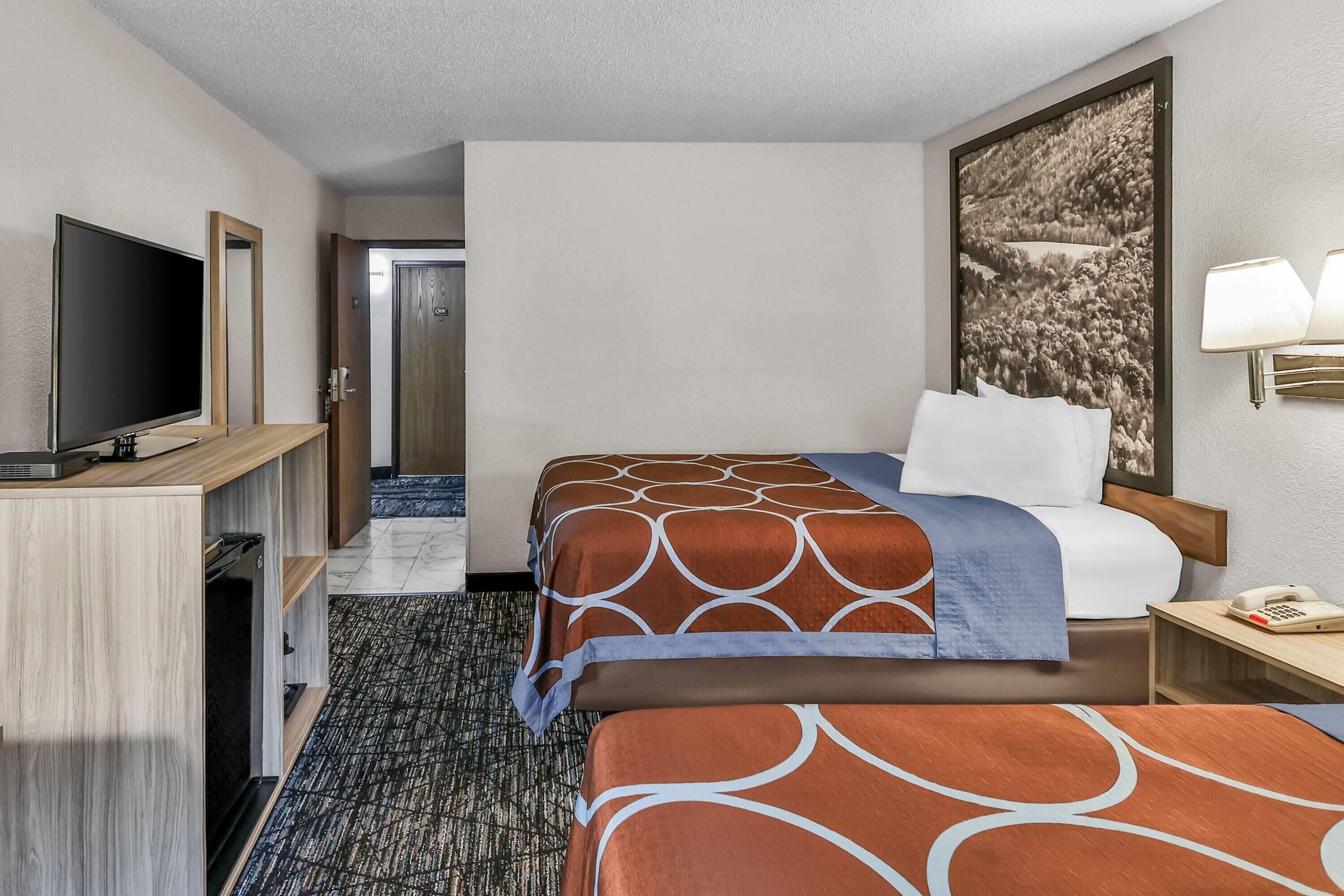 Ein Hotelzimmer mit einem Bett, einem Fernseher, einem Schreibtisch und einem Telefon.