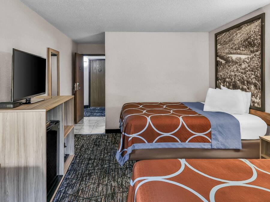 A hotel room with a bed, a television, a desk, and a phone.