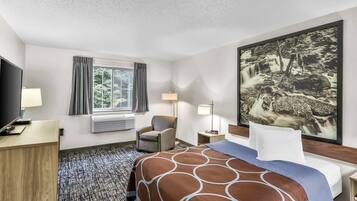A hotel room with a bed, a desk, a chair, a TV, a window with curtains, a painting, and a lamp.