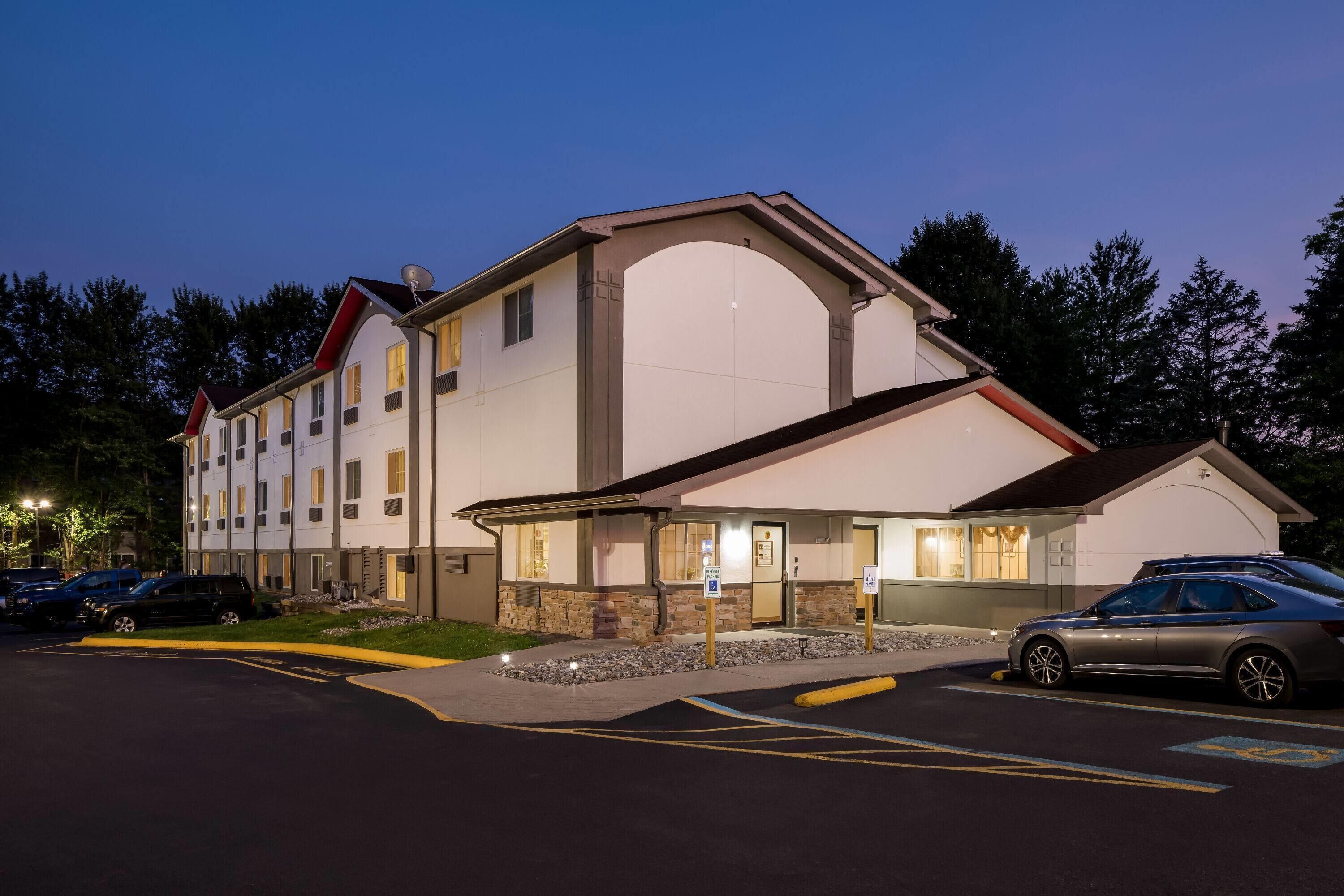 A multi-story hotel with a parking lot and a driveway leading to the entrance.