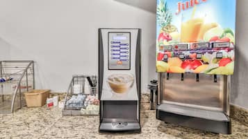 Uma máquina de café e um dispensador de suco em uma bancada de cozinha.