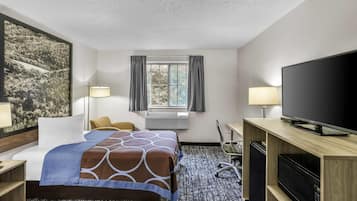 Una habitación de hotel con una cama, un escritorio, un televisor y una ventana con cortinas.