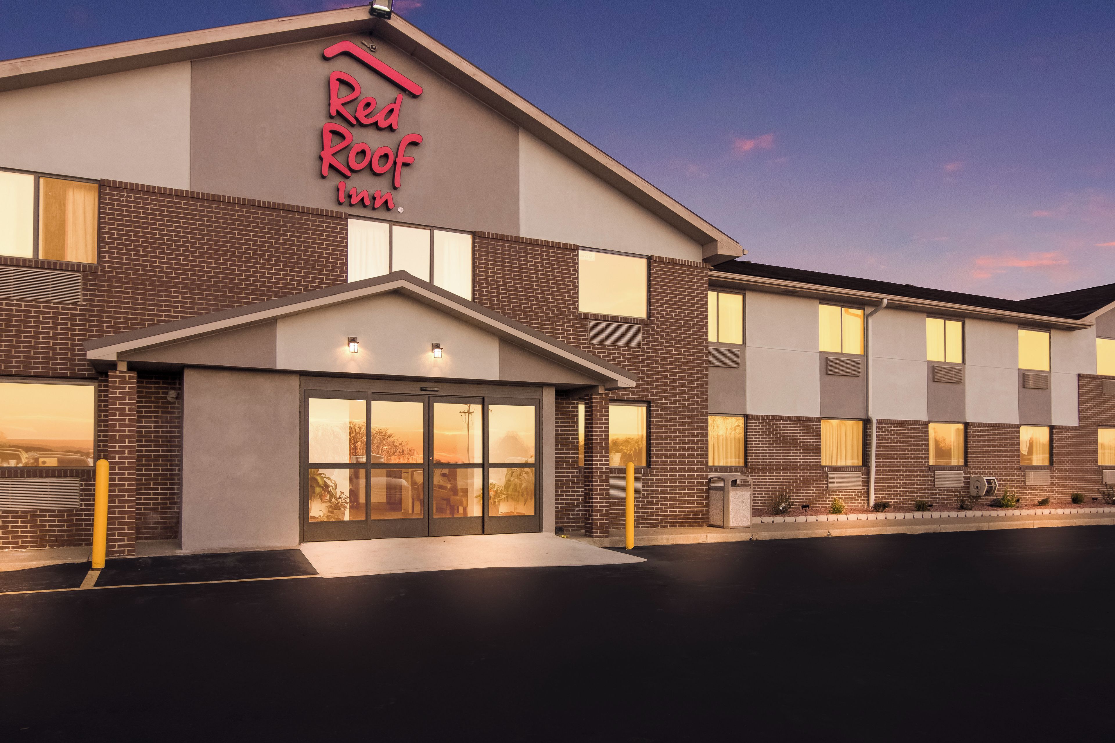 A Red Roof Inn building with a brick facade, large windows, and a neon sign.