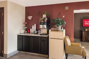 Una cocina equipada con refrigerador, cafetera y una planta en la encimera.