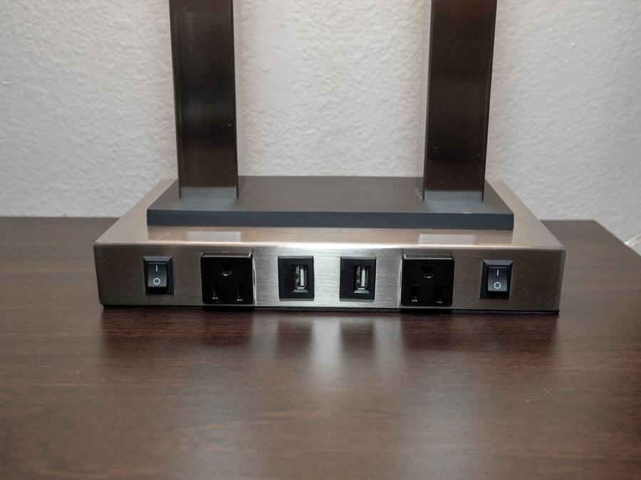 Tira-cabos com várias tomadas e portas USB sobre uma superfície de madeira.