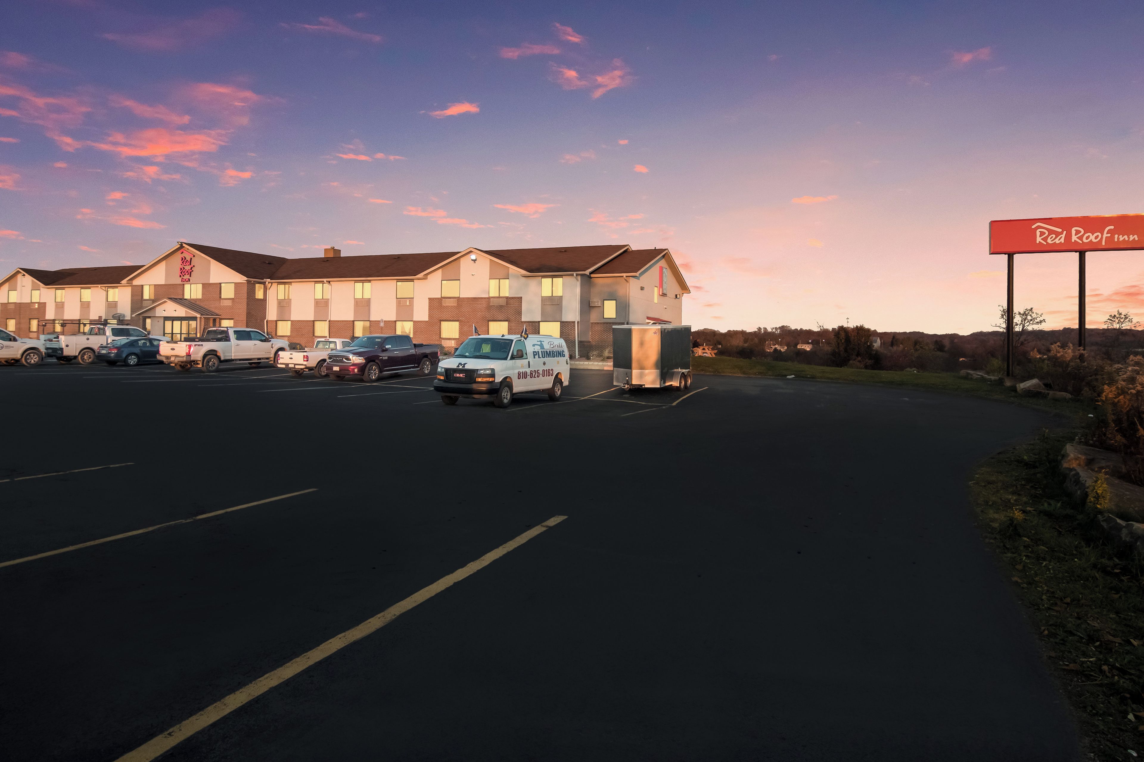 A Red Roof Inn with a parking lot and several vehicles.