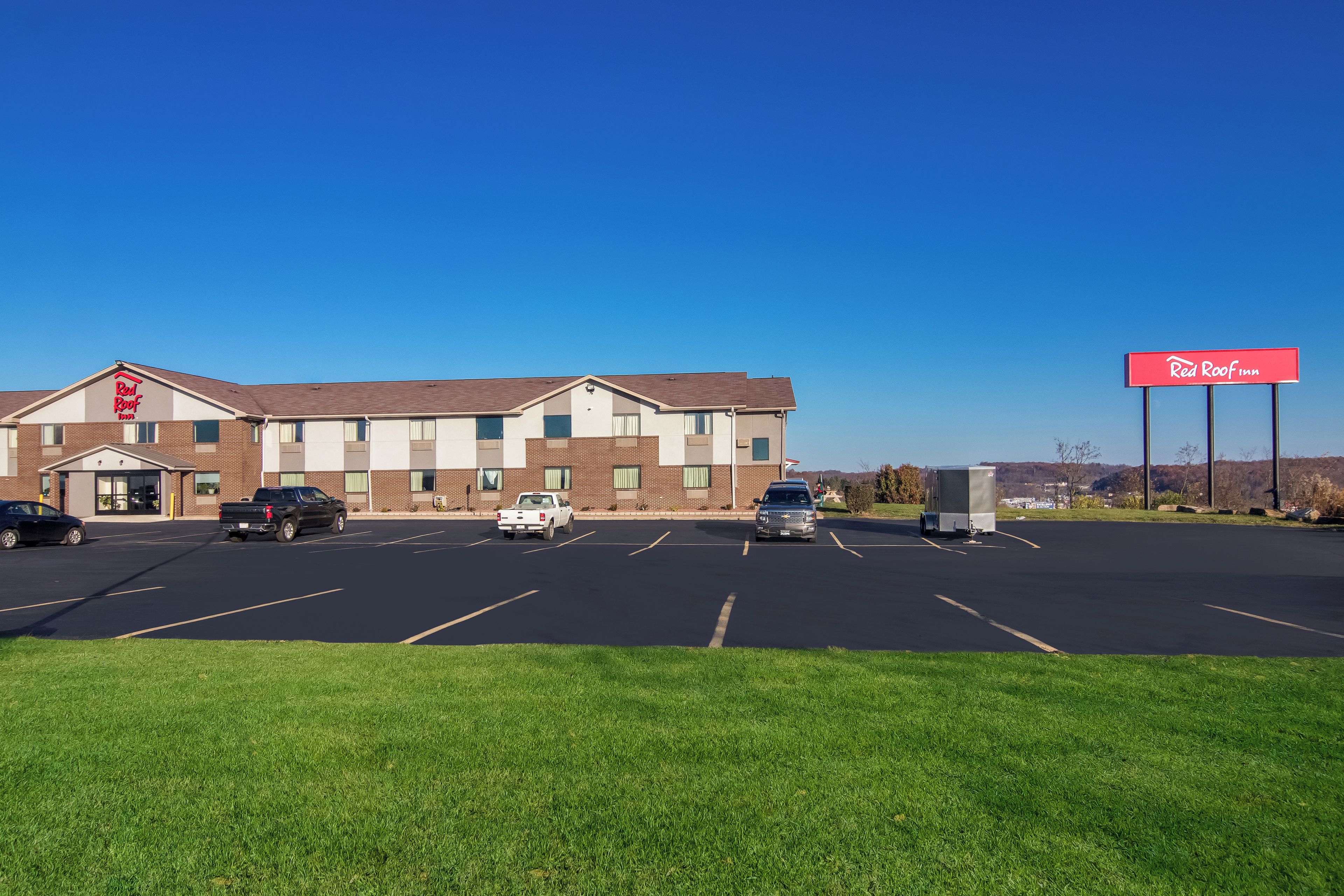 A Red Roof Inn with a parking lot and a grassy area in front.
