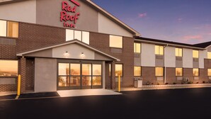 Un Red Roof Inn con fachada de ladrillo, ventanas amplias y una entrada bien iluminada.