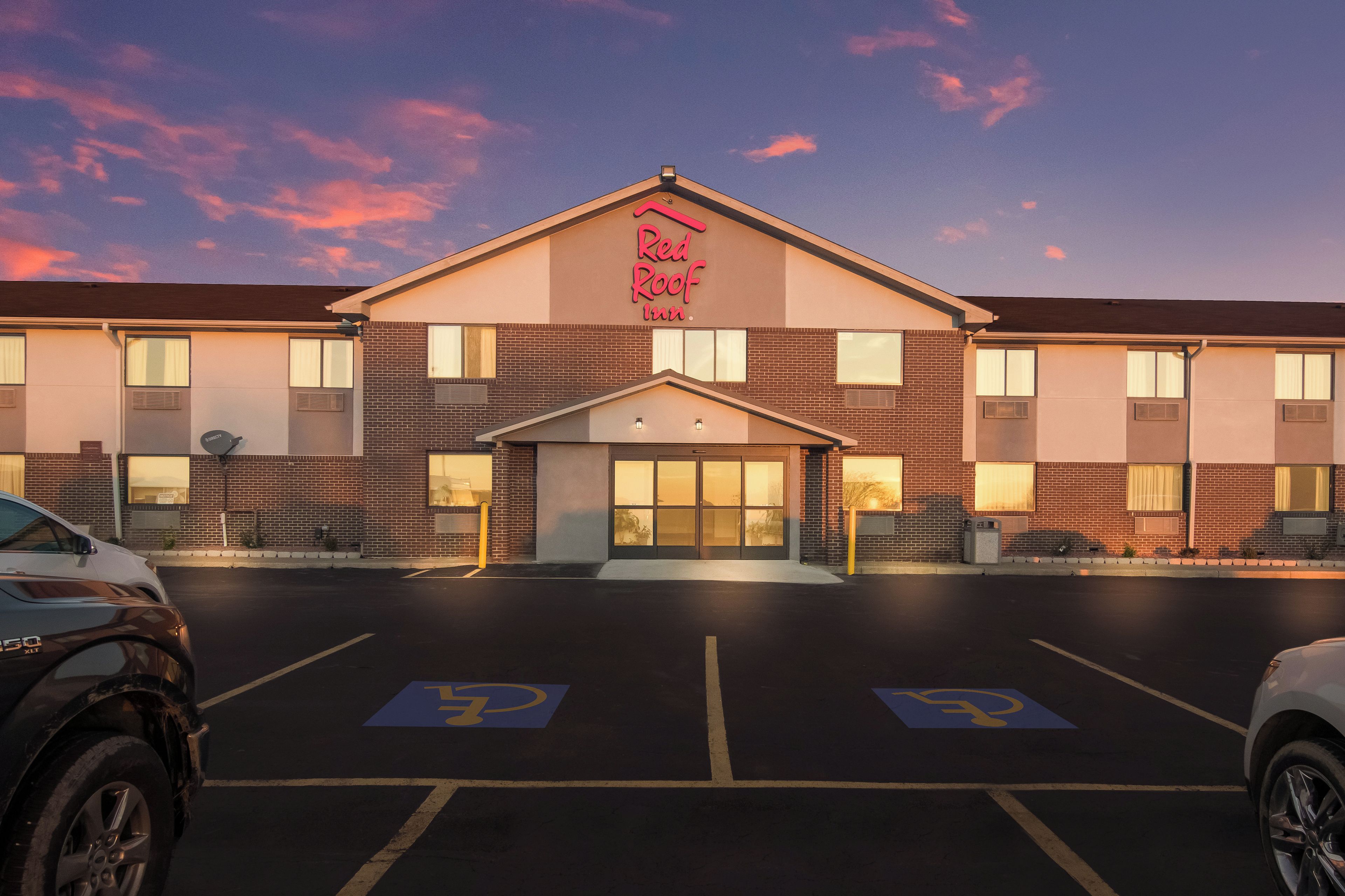 A Red Roof Inn with a brick facade, a central entrance, and a parking lot with handicapped parking spaces.