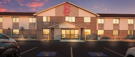 Un Red Roof Inn con fachada de ladrillo, entrada central y estacionamiento con espacios reservados para discapacitados.