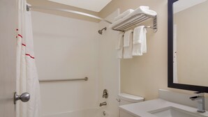 Un baño con ducha, inodoro, lavabo y toallero con varias toallas.