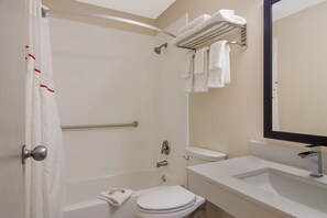 Un baño con ducha, inodoro, lavabo y toallero con varias toallas.