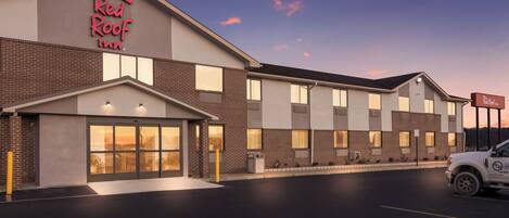 A Red Roof Inn with a brick facade, large windows, and a parking lot with a handicapped parking space.