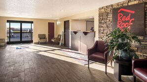 Un vestíbulo de hotel con una recepción, zona de estar y vistas a través de puertas de cristal.