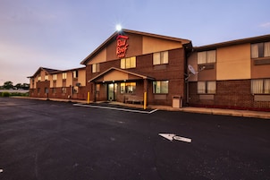 Un Red Roof Inn con fachada de ladrillo, estacionamiento y cielo despejado.