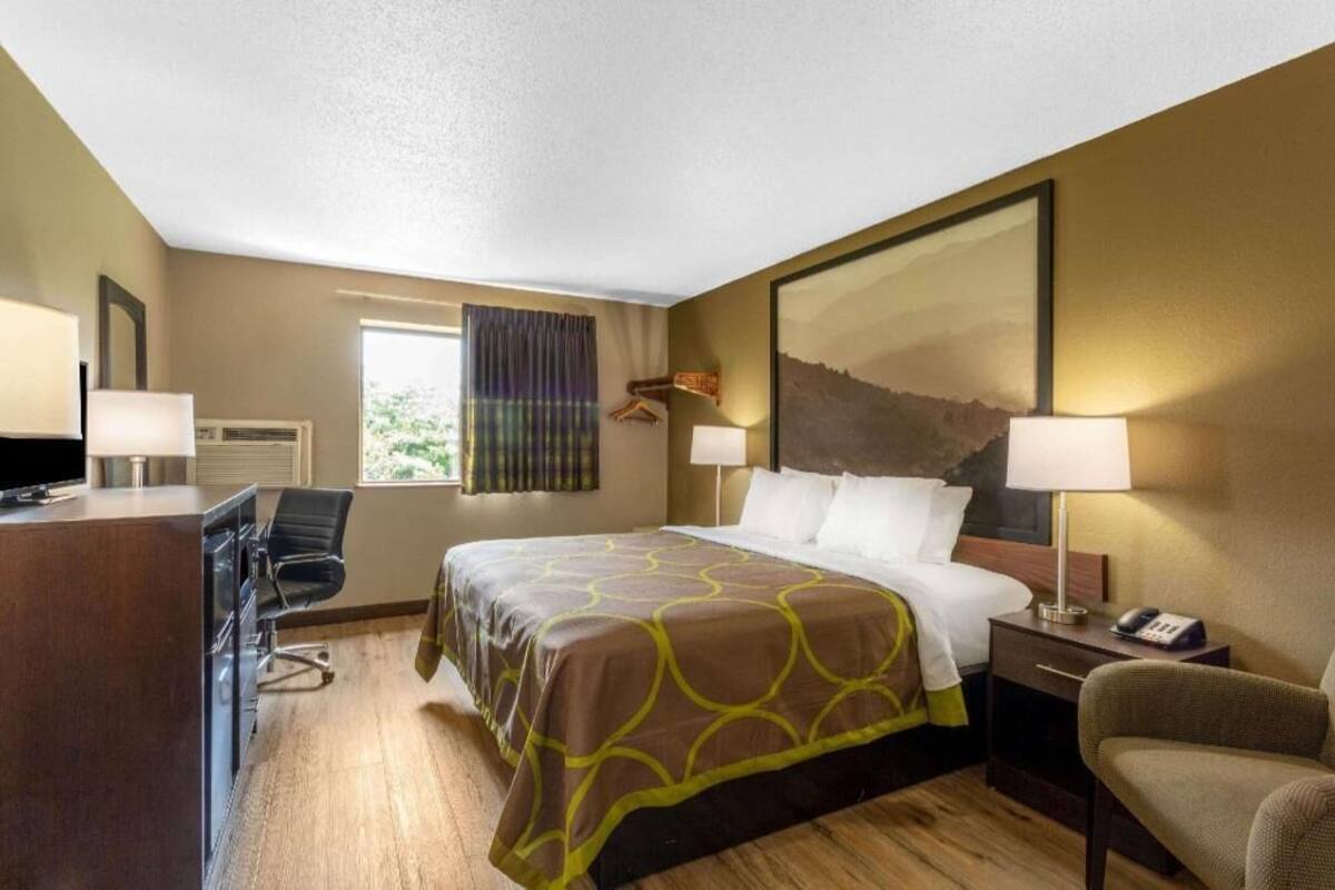 Ein Hotelzimmer mit Bett, Schreibtisch, Stuhl und einem großen Gemälde an der Wand.