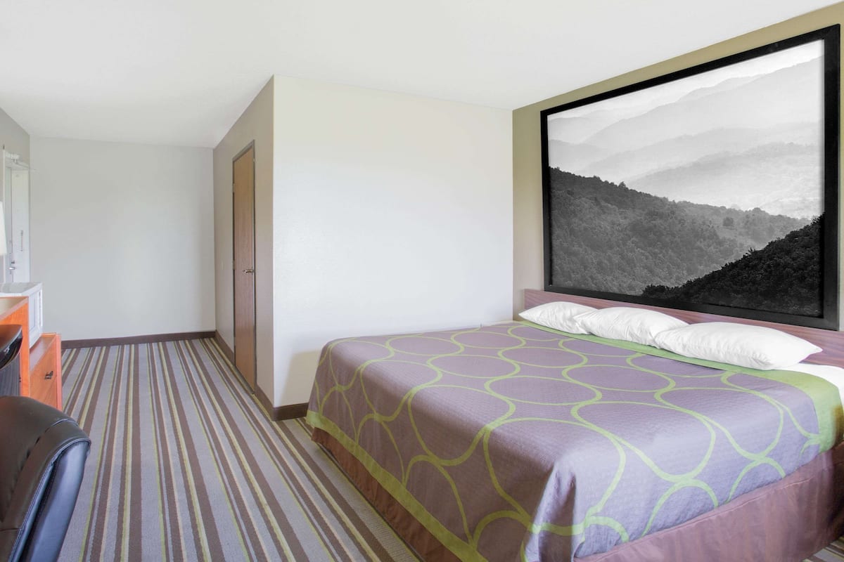 A hotel room with a bed, a desk, and a large window with a mountain view.