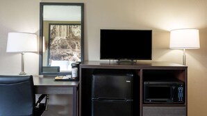 Une chambre d’hôtel équipée d’un bureau, d’une télévision à écran plat, d’un réfrigérateur, d’un four à micro-ondes et d’une chaise.