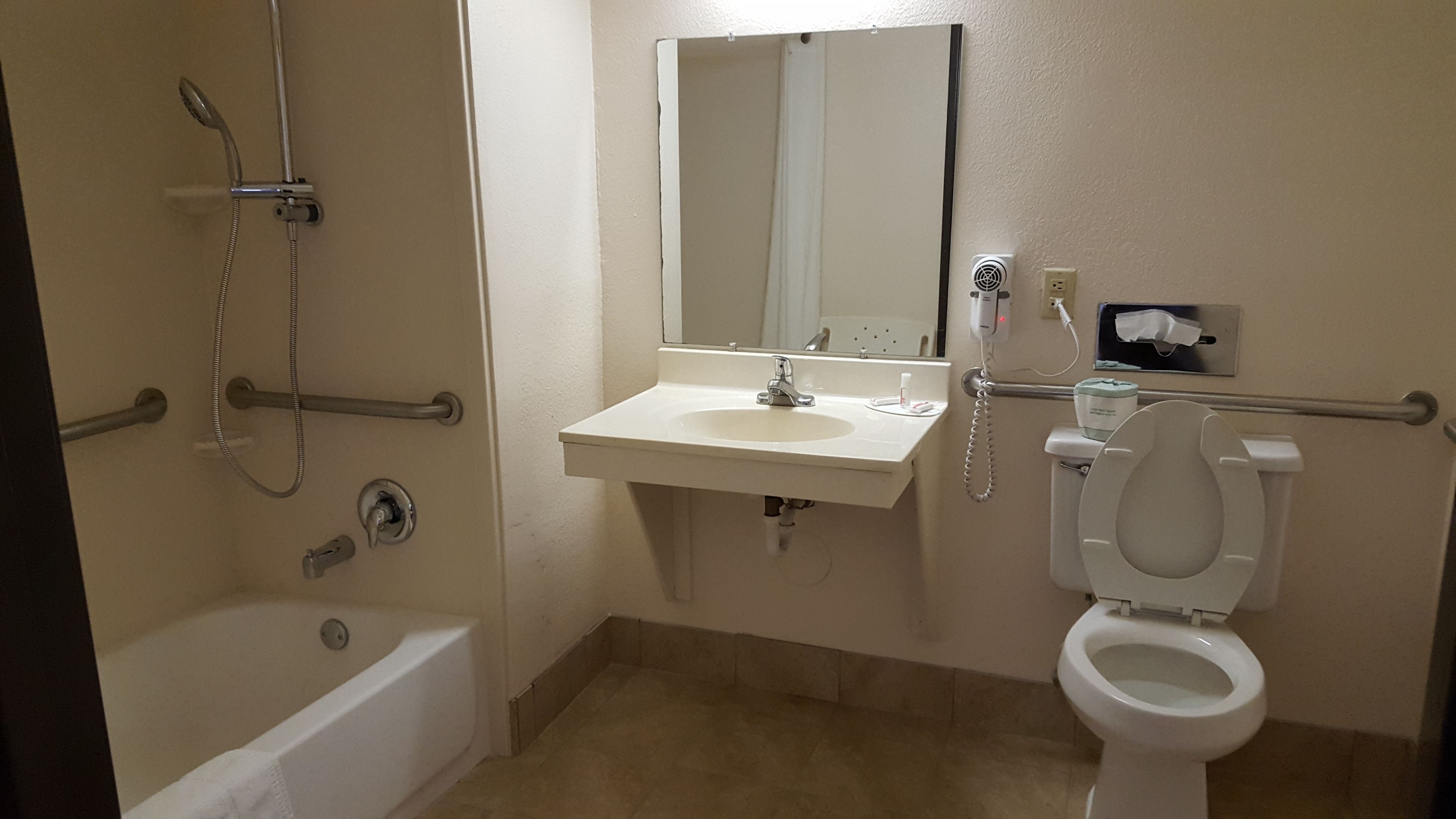 A bathroom with a bathtub, a sink, a toilet, and a mirror.