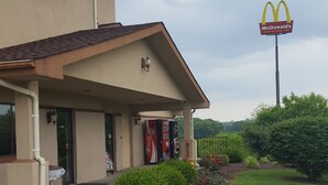 Un motel de la chaîne Super 8 avec un réfrigérateur contenant des boissons Coca-Cola et Pepsi, un distributeur automatique de Coca-Cola, et une enseigne McDonald's en arrière-plan.
